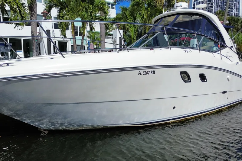 Slide: The Image of 2008 Sea Ray Sundancer 330 yacht docked near palm trees and modern buildings. - 10