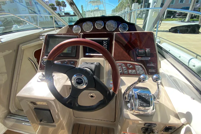 Slide: The Image of 2008 Sea Ray Sundancer 330 helm with steering wheel, gauges, and controls in a marina setting. - 36