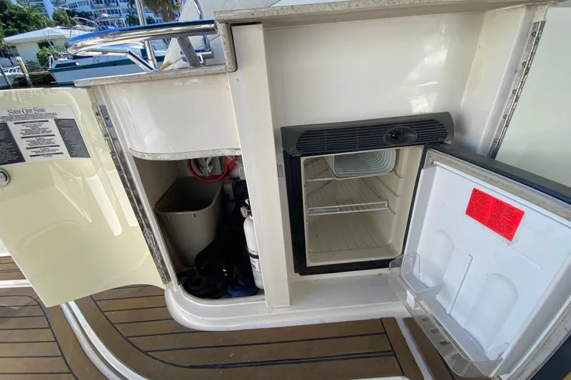 Slide: The Image of 2008 Sea Ray Sundancer 330 boat interior with open mini fridge and storage compartment. - 54