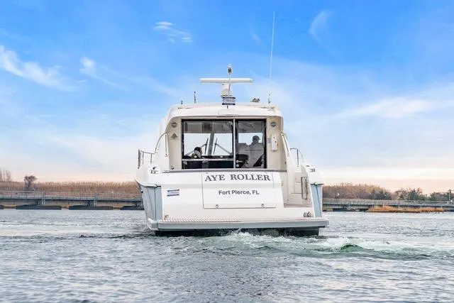 Slide: The Image of 2014 Riviera 4400 Sport Yacht cruising on water, rear view, clear blue sky. - 10
