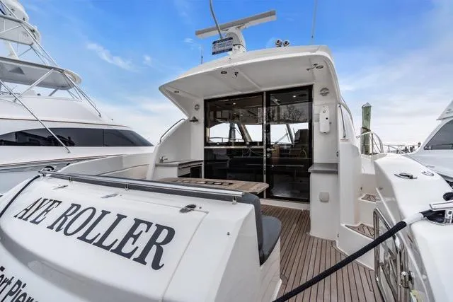 Slide: The Image of 2014 Riviera 4400 Sport Yacht with open deck and sleek design, docked under blue sky. - 25