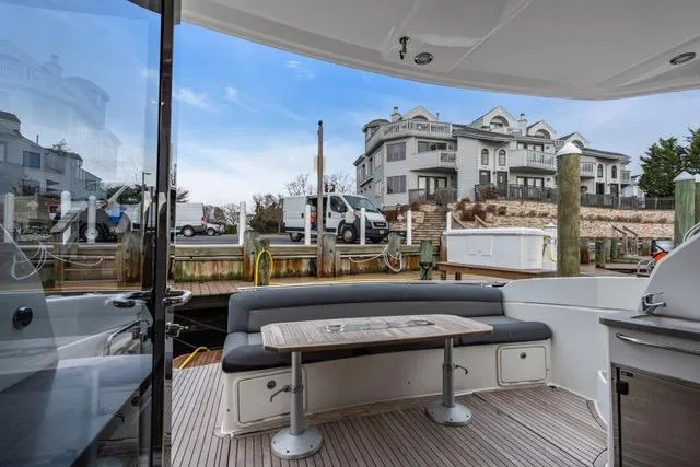 Slide: The Image of 2014 Riviera 4400 Sport Yacht docked, featuring outdoor seating and scenic waterfront view. - 28