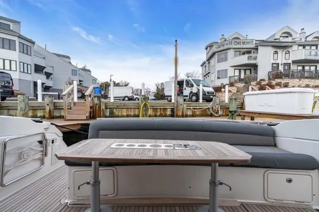 Slide: The Image of 2014 Riviera 4400 Sport Yacht docked, featuring a spacious outdoor seating area with a table. - 30