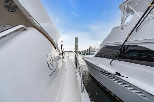 Slide: The Image of 2014 Riviera 4400 Sport Yacht docked alongside another boat under a clear blue sky. - 32