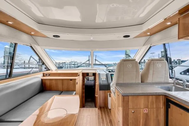 Slide: The Image of 2014 Riviera 4400 Sport Yacht interior with modern seating and panoramic windows. - 40