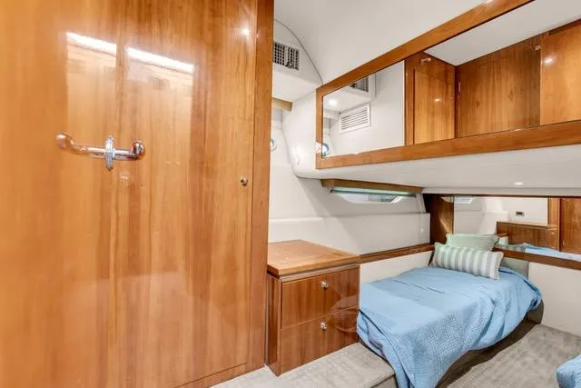 Slide: The Image of 2014 Riviera 4400 Sport Yacht cabin with wooden interior and cozy bed. - 54