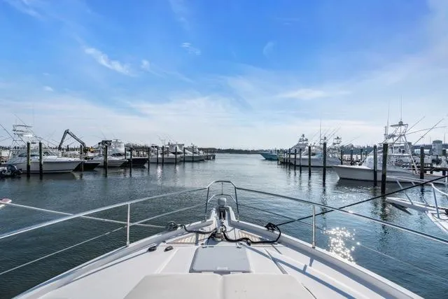 Slide: The Image of Bow view from 2014 Riviera 4400 Sport Yacht in a marina under clear blue skies. - 68