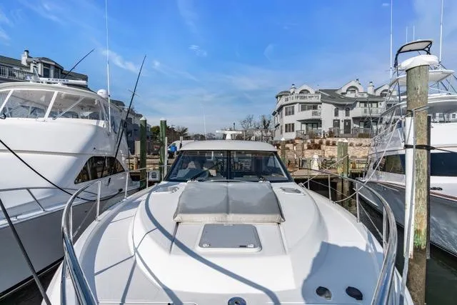 Slide: The Image of 2014 Riviera 4400 Sport Yacht docked at a marina with waterfront buildings. - 72