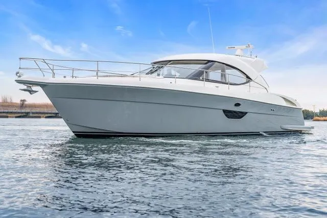 Slide: The Image of 2014 Riviera 4400 Sport Yacht on calm water under a clear blue sky. - 8