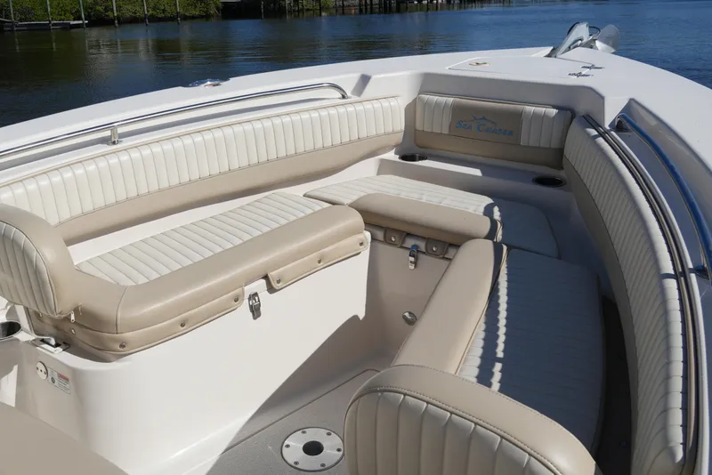 Slide: The Image of 2019 SeaChaser 24 HFC boat interior with beige and white seating, near calm water. - 9