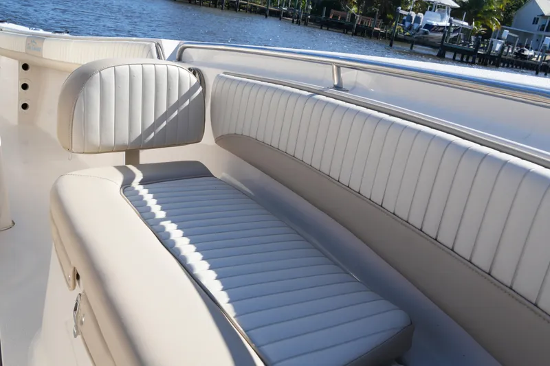 Slide: The Image of 2019 SeaChaser 24 HFC boat interior with white cushioned seating by the water. - 12