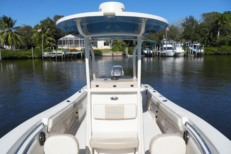 Slide: The Image of 2019 SeaChaser 24 HFC boat on calm water, surrounded by lush greenery and docked boats. - 28