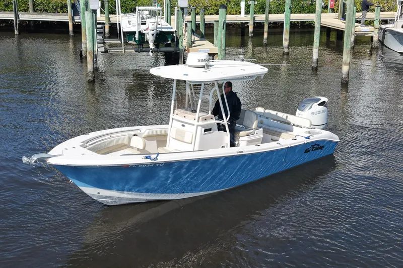 Slide: The Image of 2019 SeaChaser 24 HFC boat in water near dock, featuring blue hull and Suzuki engine. - 8