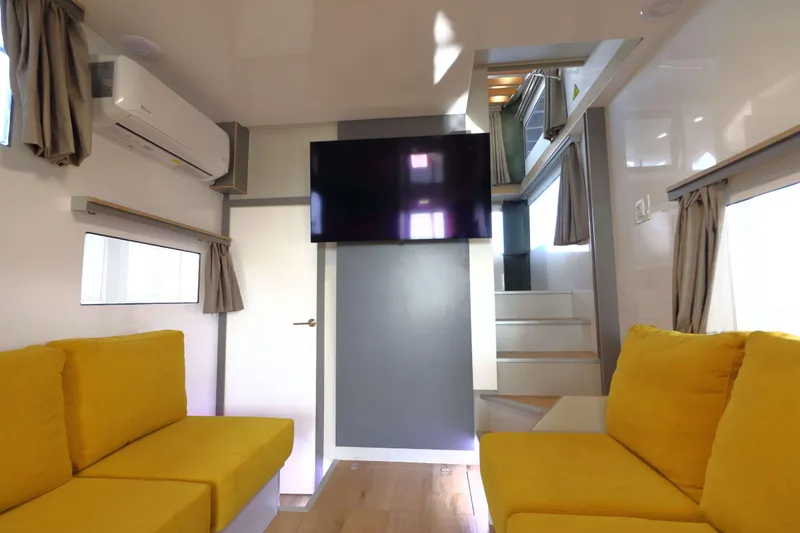 Slide: The Image of Modern Navisyo Homes NV.08 interior with yellow seating, TV, and stairs, 2021 model. - 4