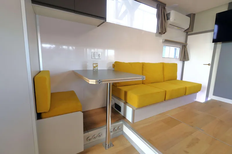 Slide: The Image of Modern Navisyo Homes NV.08 interior with yellow seating, compact dining area, and sleek design. - 5