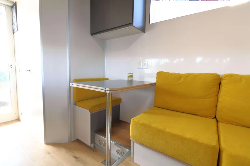 Slide: The Image of Modern Navisyo Homes NV.08 interior with yellow seating and compact dining area, 2021 model. - 6