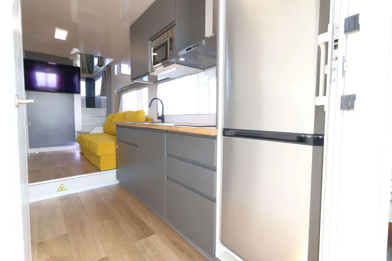 Slide: The Image of Modern Navisyo Homes NV.08 interior with sleek kitchen, yellow sofa, and wall-mounted TV, 2021 model. - 9