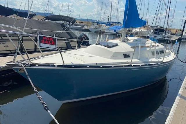 Slide: The Image of 1977 C&C 29 sailboat for sale, docked in marina with blue hull and white deck. - 29