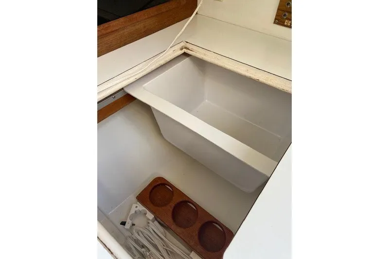 Slide: The Image of 1977 C&C 29 sailboat interior storage compartment with wooden trim and cup holders. - 4