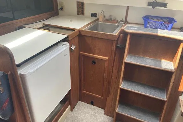 Slide: The Image of 1977 C&C 29 yacht interior with kitchenette, sink, and wooden steps. - 8