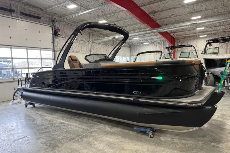 The Image of 2026 Sylvan L-5 Platinum pontoon boat in showroom, sleek black design, modern interior. - 1