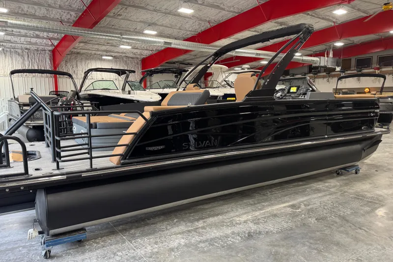 Slide: The Image of 2026 Sylvan L-5 Platinum pontoon boat in showroom, featuring sleek black design and modern amenities. - 3