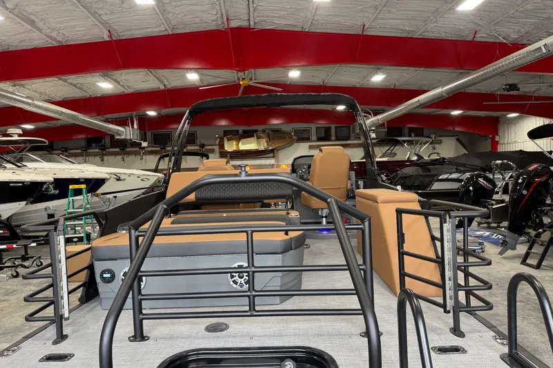 Slide: The Image of 2026 Sylvan L-5 Platinum pontoon boat in showroom with red ceiling and other boats. - 8