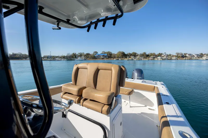Slide: The Image of 2022 Sea Hunt Gamefish 25 boat interior with tan seating on calm water. - 14