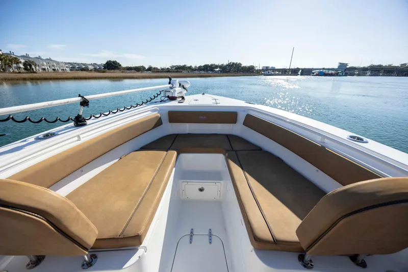 Slide: The Image of 2022 Sea Hunt Gamefish 25 boat interior with tan seating, on calm water. - 16