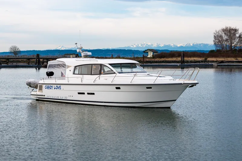 Slide: The Image of 2023 Nimbus 405 Coupé yacht on calm water with scenic mountain backdrop. - 19