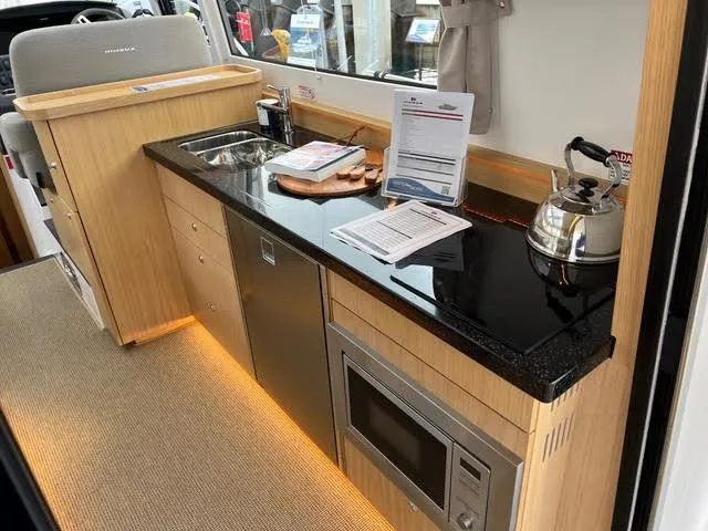 Slide: The Image of 2023 Nimbus 405 Coupé boat named "Crazy Love" docked in a serene marina. - 9