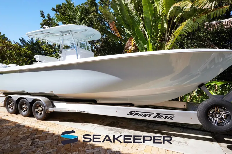 The Image of 2024 Contender 35 ST boat on Sport Trail trailer, surrounded by lush greenery. - 0