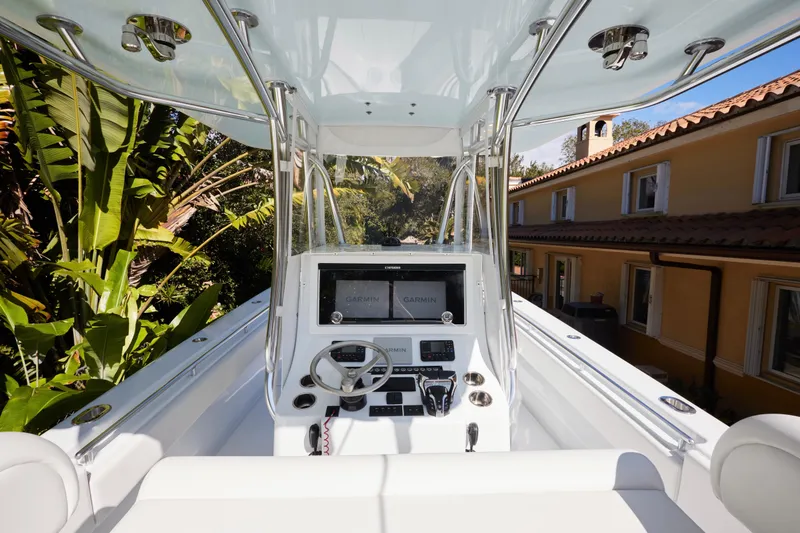 Slide: The Image of 2024 Contender 35 ST boat cockpit with Garmin navigation, surrounded by tropical foliage. - 10
