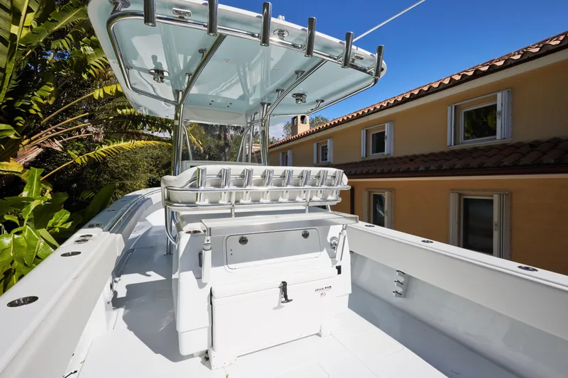 Slide: The Image of 2024 Contender 35 ST boat with T-top, rod holders, and sleek design near a house. - 13