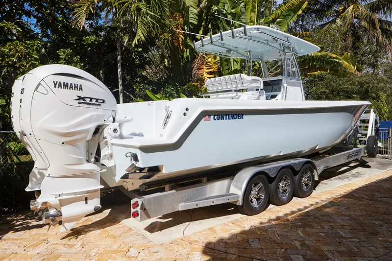 Slide: The Image of 2024 Contender 35 ST boat on trailer with Yamaha XTO engine, surrounded by tropical foliage. - 3