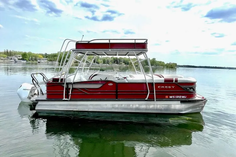 The Image of 2019 Crest 250 LUSD pontoon boat on a calm lake with scenic background. - 0