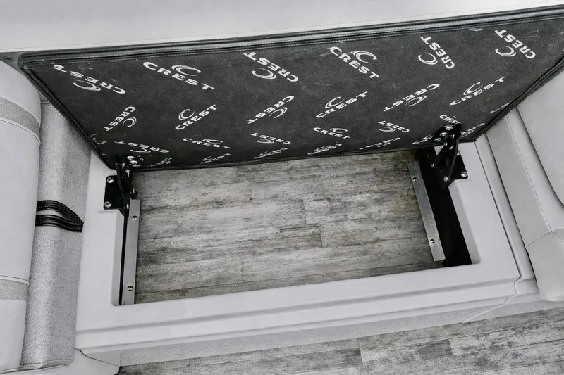 Slide: The Image of Open storage compartment in 2019 Crest 250 LUSD boat, featuring branded interior panel. - 32