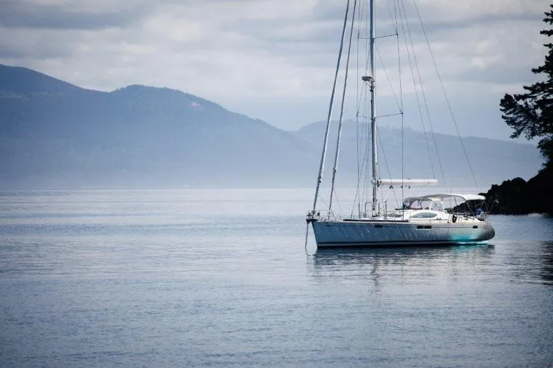 Slide: The Image of Sailboat Jeanneau Sun Odyssey 54 DS, 2007, anchored on calm water with mountainous backdrop. - 14