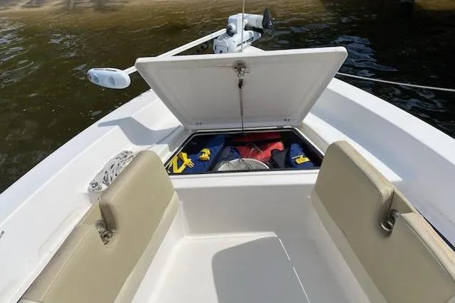 Slide: The Image of 2009 Cobia 191 Bay boat with open storage compartment, beige seating, and visible life jackets. - 6
