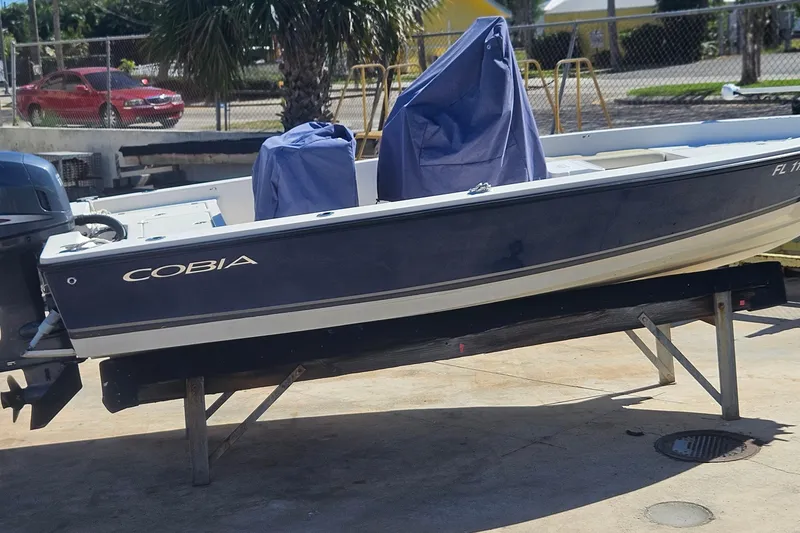Slide: The Image of 2009 Cobia 191 Bay boat on a stand, covered, with a motor, outdoors. - 7