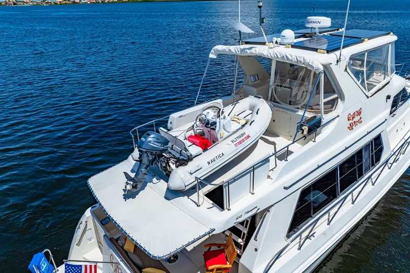 Slide: The Image of 2007 Hampton 558 Pilothouse yacht with dinghy on deck, cruising on calm blue waters. - 80