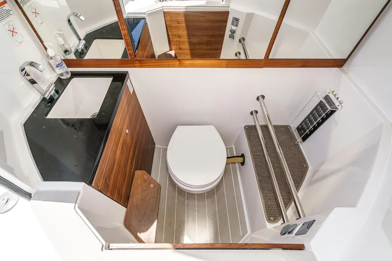 Slide: The Image of 2019 Axopar 28 CABIN bathroom with sink, toilet, and wooden accents. - 12