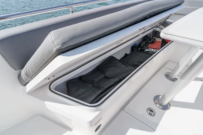 Slide: The Image of 2019 Axopar 28 CABIN boat storage compartment with open lid, revealing interior contents. - 15