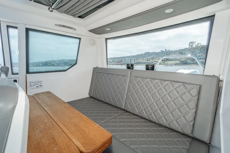Slide: The Image of Interior of 2019 Axopar 28 CABIN with gray seating and wooden table, overlooking water. - 27