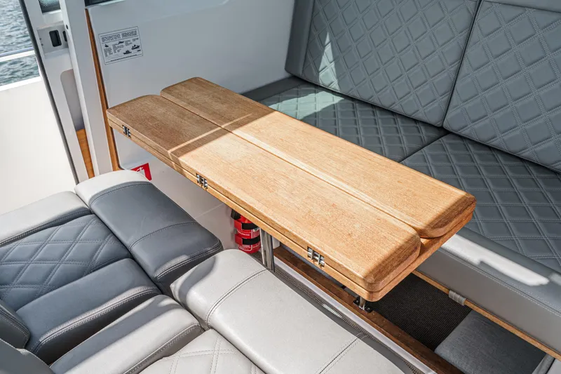 Slide: The Image of 2019 Axopar 28 CABIN interior with wooden table and quilted seating. - 29