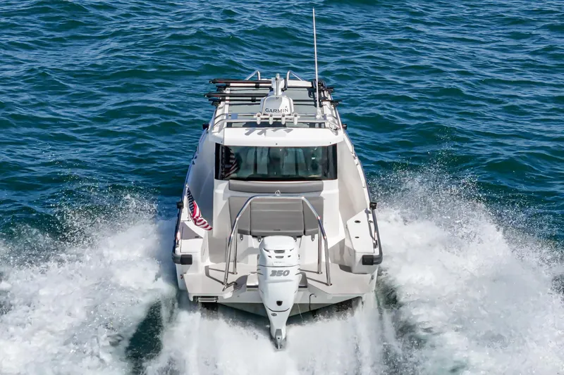 Slide: The Image of 2019 Axopar 28 CABIN boat cruising on open water, rear view. - 3