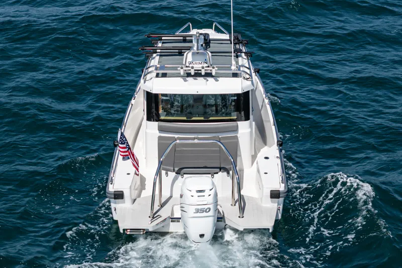 Slide: The Image of 2019 Axopar 28 CABIN boat cruising on open water, rear view. - 34