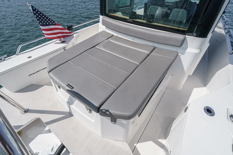 Slide: The Image of 2019 Axopar 28 CABIN boat with gray seating and American flag on water. - 38