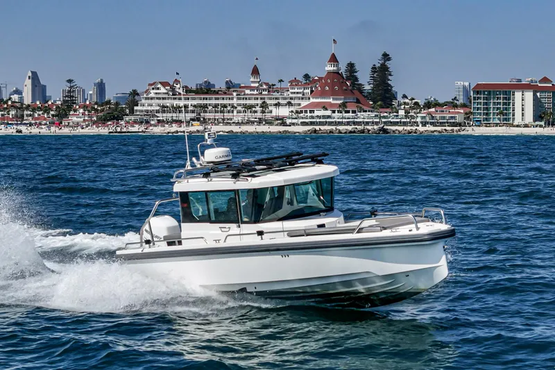 Slide: The Image of 2019 Axopar 28 CABIN cruising near a coastal cityscape with historic architecture. - 4
