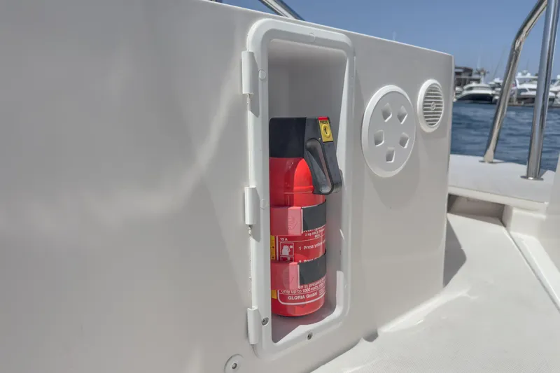 Slide: The Image of Fire extinguisher in compartment on 2019 Axopar 28 CABIN boat, docked by the water. - 43